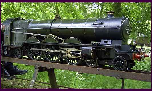 A dark green 4-6-2 model steam locomotive on a raised outdoor track