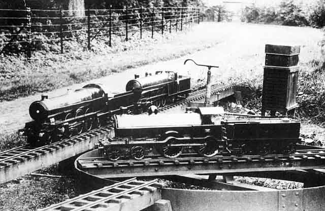 A model steam locomotive on an outdoor turntable, with two more locomotives on an adjacent track